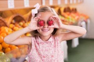 Girl holding two tomatoes in front of her eyes