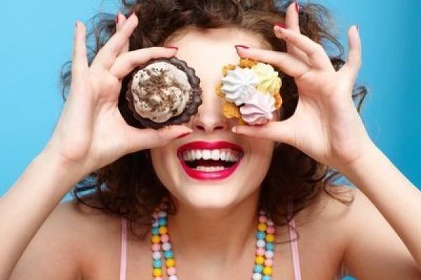 Woman holding cupcakes in front of her eyes