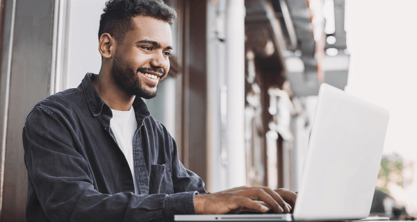 Guy writing on his laptop smiling