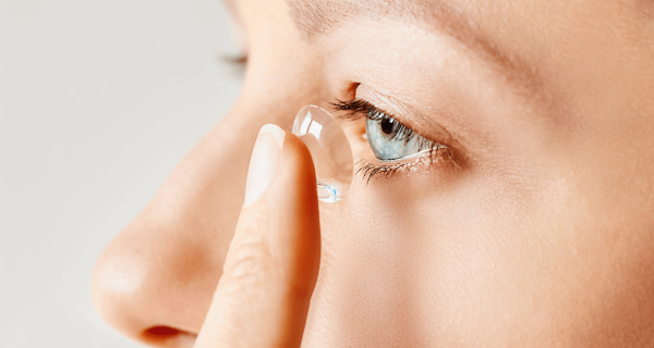 Blue eyed girl putting in a contact lense