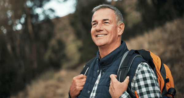 Older man with backpack on outside, smiling