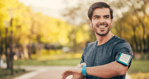 Man outside, smiling while checking his watch